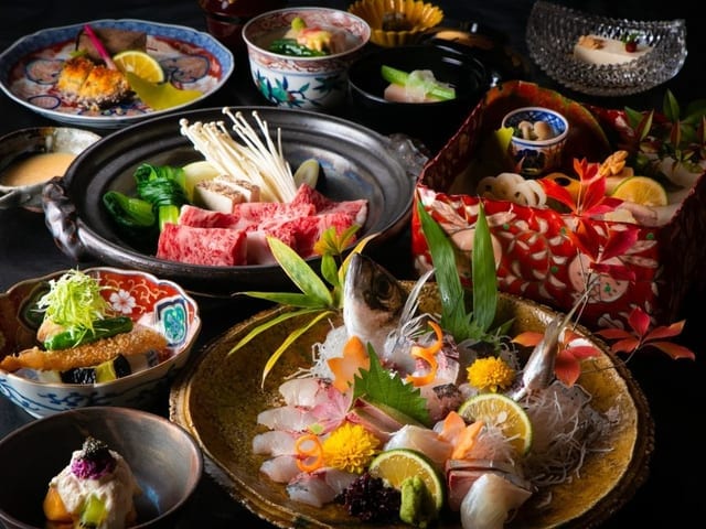 会席料理。造りと小鍋、前菜が卓一面に並ぶ