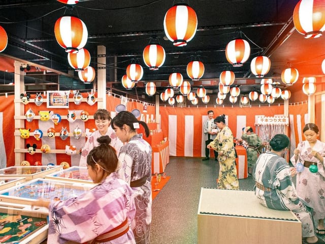 夜ごと開かれるお祭り広場。赤白の提灯の下に射的や輪投げが並ぶ