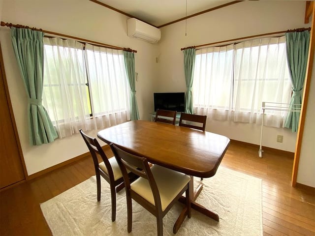 離れの客室。窓が並ぶ明るい部屋に机と椅子が置かれている