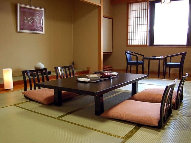 12畳の和室。座卓を囲む座椅子が並び、障子から光が入る