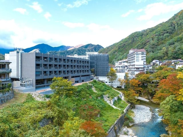 利根川の渓谷に建つ宿の全景。川沿いに色づき始めた木々が続く