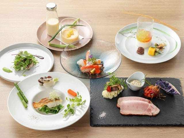 夕食の一皿。白い皿に前菜と魚、彩りの野菜が並ぶ