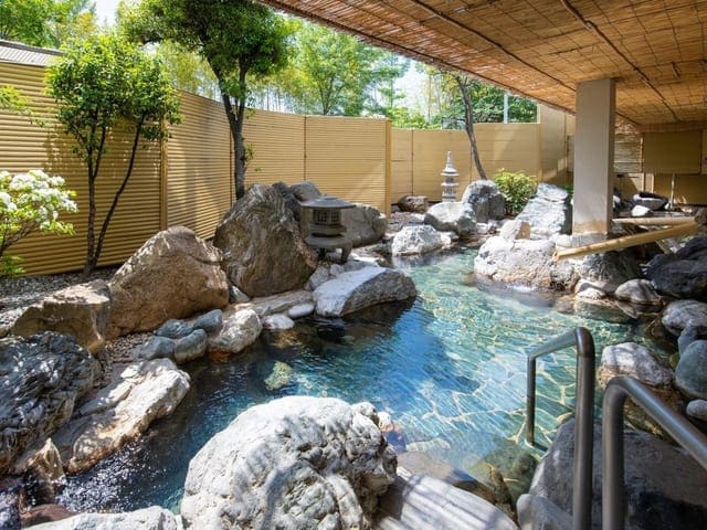 岩の大露天風呂「六花仙」。広い湯船を岩と木々が囲む