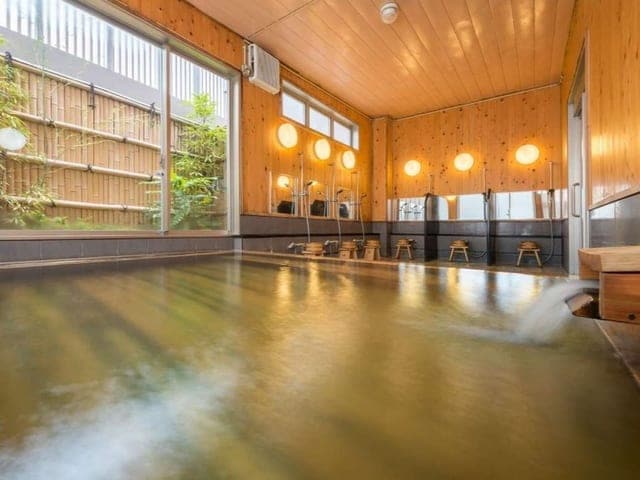 檜の大浴場。木の湯船に湯気が立ち、窓から光が入る