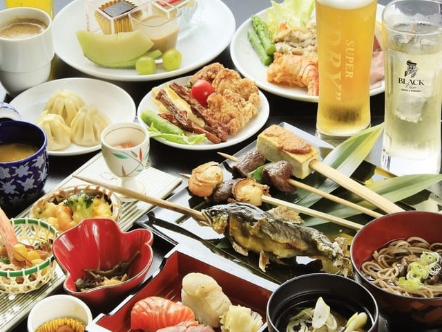 会席料理の膳。天ぷらと小鉢、笹に載せた前菜が並ぶ