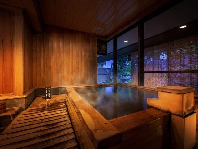 青森ヒバの内湯。湯気の立つ湯船の奥に格子窓が続く
