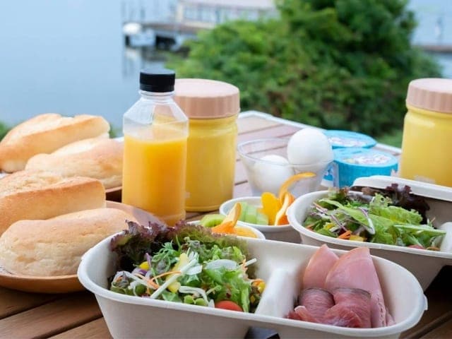 朝食。パンとサラダ、ジュースが窓辺のテーブルに並ぶ