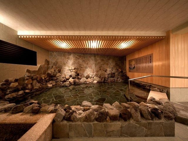 大浴場「桃源」。岩を組んだ湯船が石畳の床に沈む