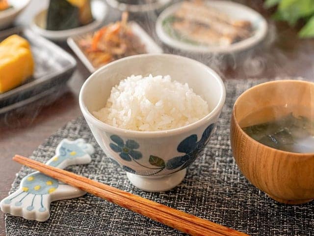 砥部焼の器で供される朝食。湯気の立つ炊きたてご飯と汁椀が並ぶ
