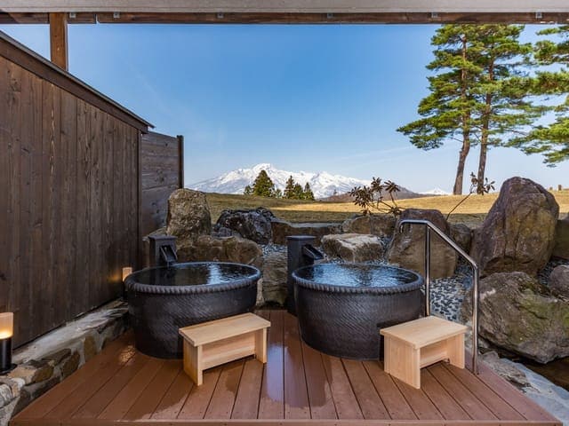 露天風呂。ウッドデッキに据えた2つの壺湯の先に、雪をかぶった妙高連峰
