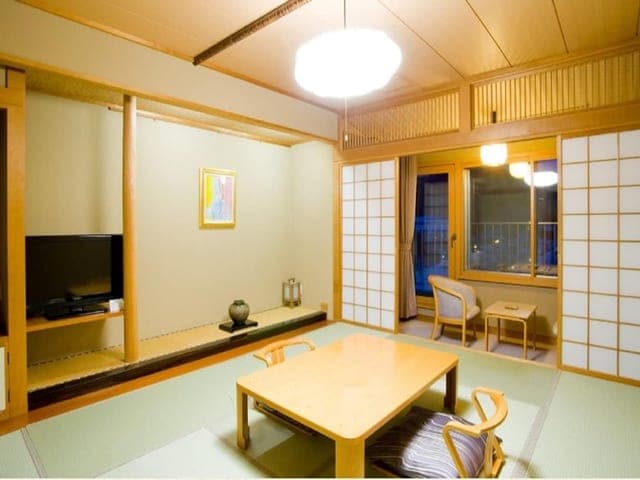 10畳の和室。座卓の向こうに障子と床の間が見える