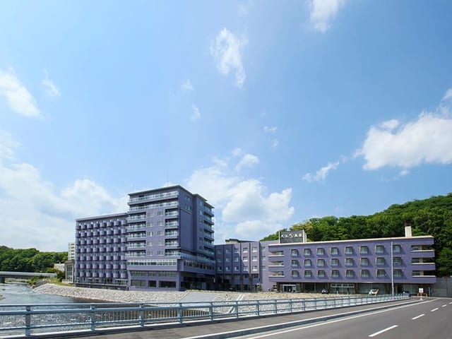 湖のほとりに建つ本館。手前に水面、背後に丘の緑