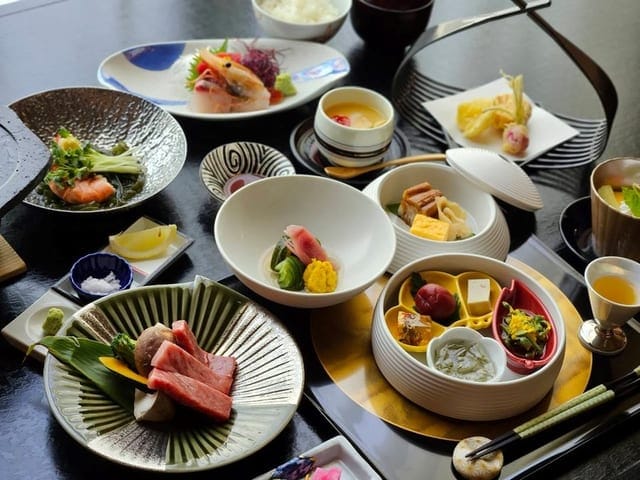 料理長お任せの会席膳。刺身と前菜が黒い折敷に並ぶ