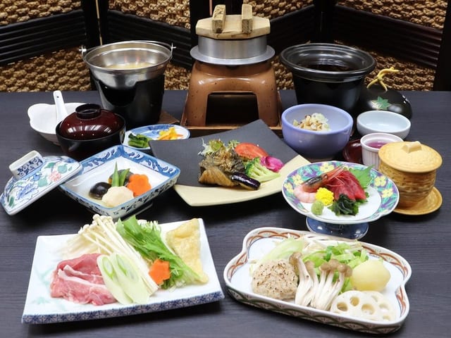 信州味覚の会席。陶板と小鍋、造りと小鉢が卓に並ぶ