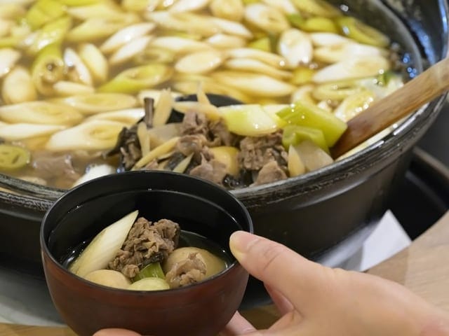 朝食の芋煮。大鍋から取り分けた椀を手に取っている
