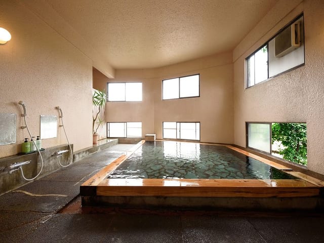 貸切の内湯。高い窓から光が入り、石造りの湯船に湯が満ちる