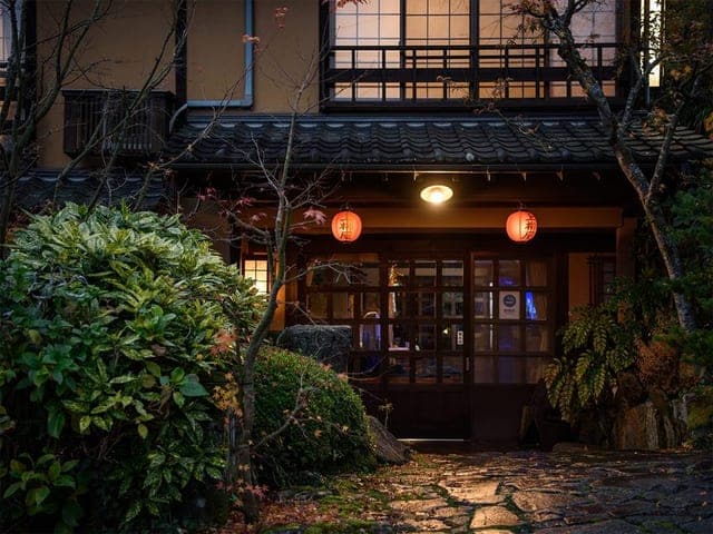 夕闇の玄関。赤い提灯が石畳のアプローチを照らす